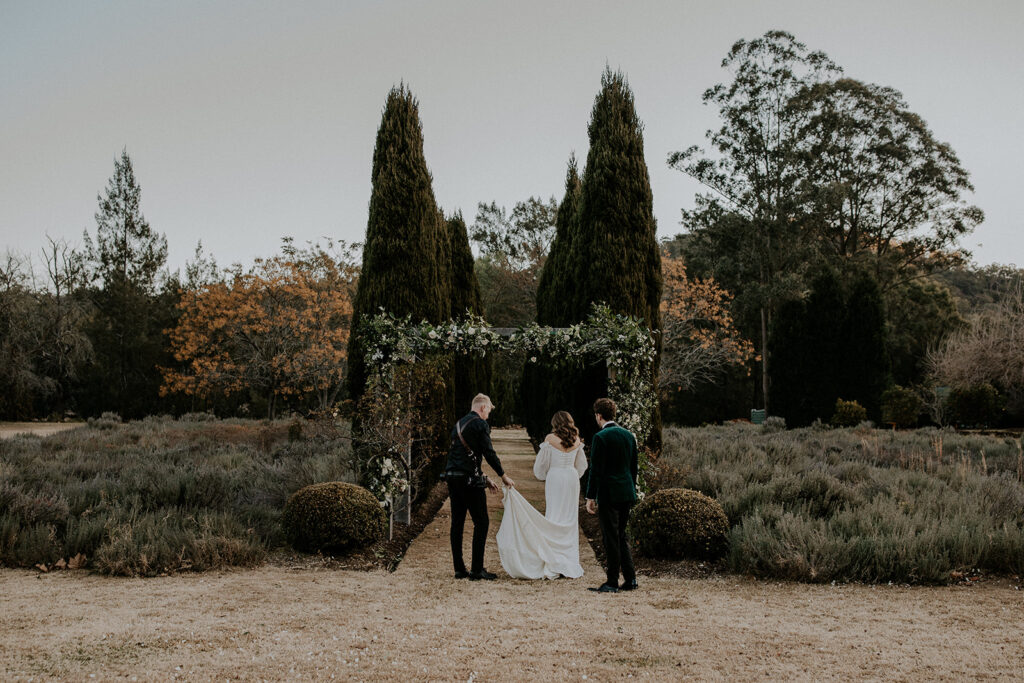 A couple is helped into position for photos by Sydney wedding photographer Scott Surplice, who helps with the brides dress