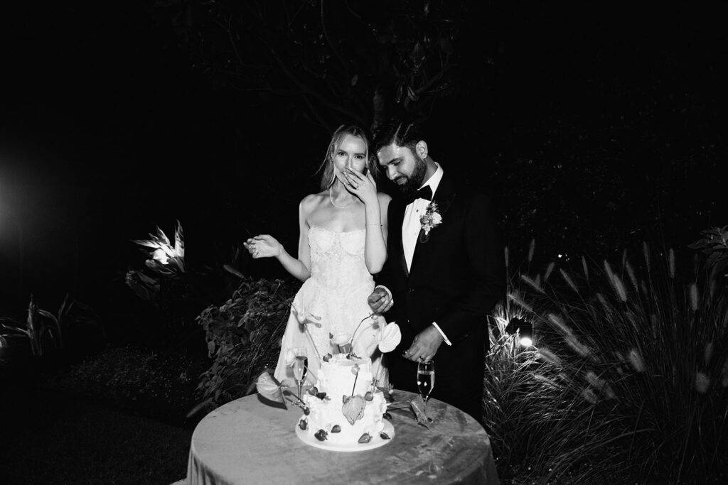 A candid image of the bride and groom cutting their wedding cake, as the bride has a taste of the cake. Captured by Sydney wedding photographer Scott Surplice