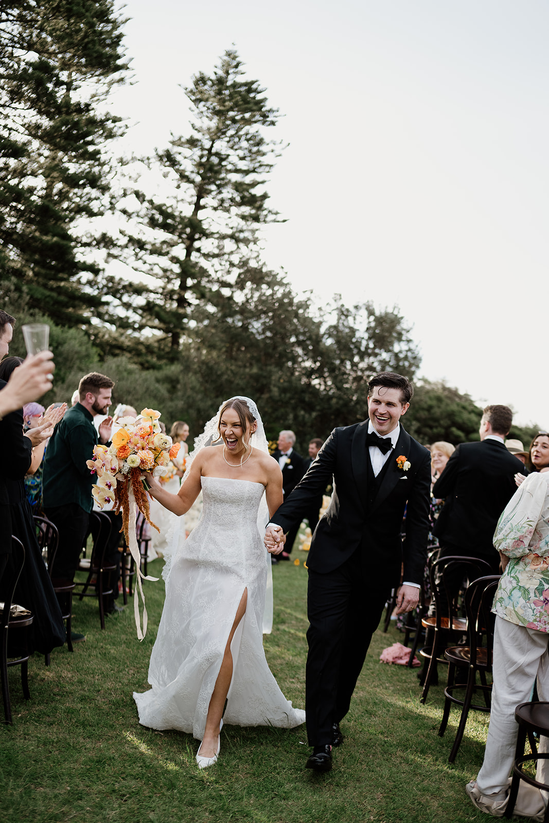 Newly married couple holding hands and walking down the aisle at Dunes